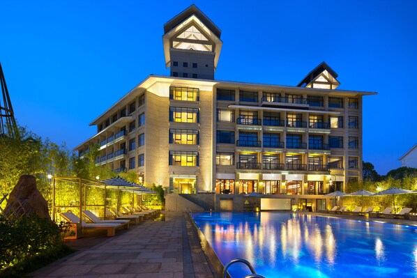 A multi-story hotel with a swimming pool, outdoor seating, and a distinctive tower-like structure. - Silver World Hotels Resorts (Dongguan)