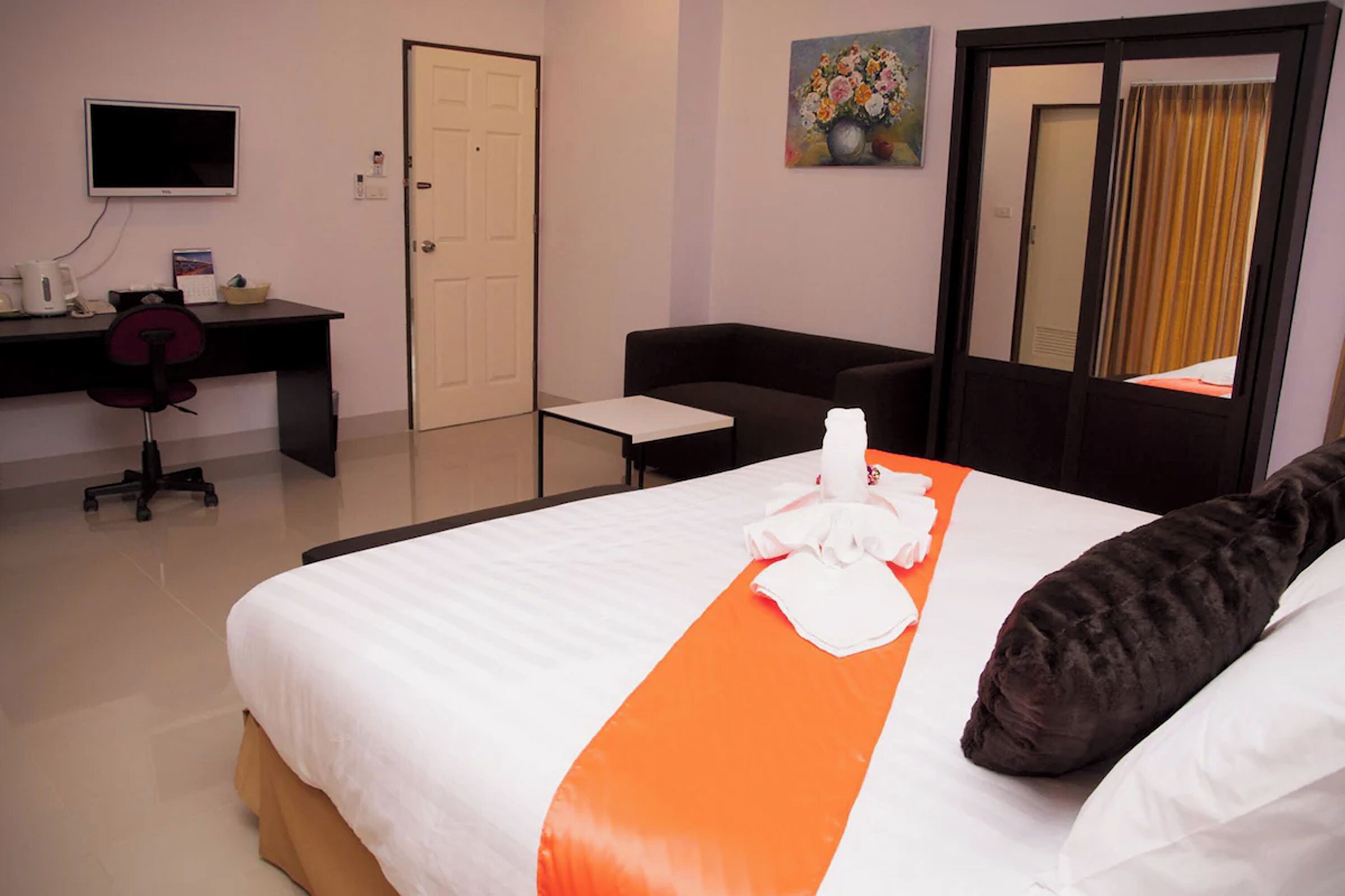 Una habitació d'hotel amb un llit, un escriptori amb una cadira, una televisió i una porta.