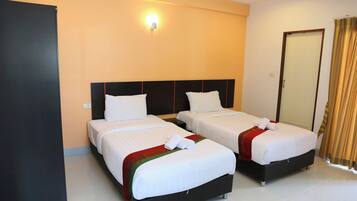 Habitación de hotel con dos camas, un armario, un espejo y una lámpara.