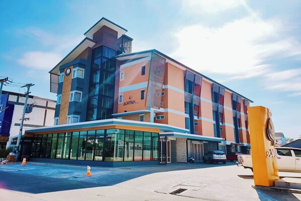 Un hôtel à plusieurs étages au design moderne, doté d’une entrée imposante avec des portes en verre et d’une façade bleue et orange.