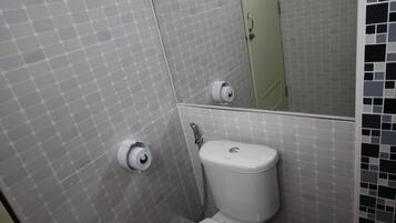 Un baño con inodoro, lavamanos, toallero y espejo.
