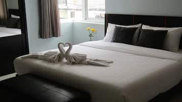 A hotel room with a large bed, a bedside table, a mirror, and a window with curtains.