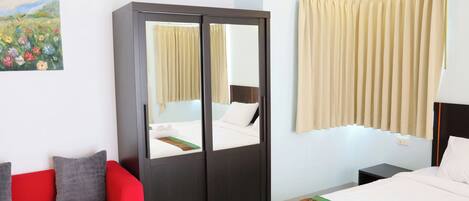 Una habitación de hotel con una cama, un sofá rojo, un armario y un cuadro en la pared.