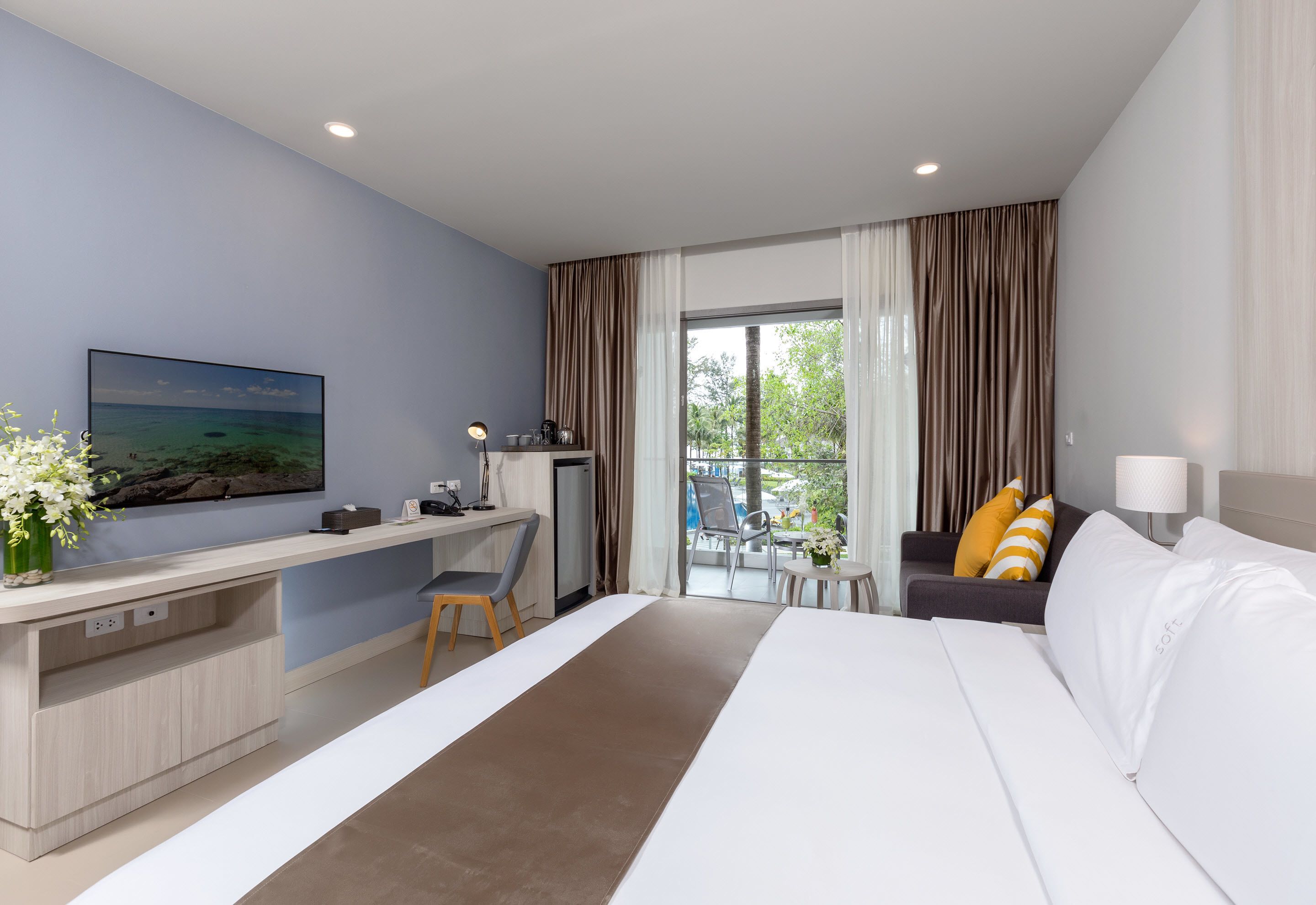 Habitación de hotel con cama, escritorio, silla y vistas al exterior.