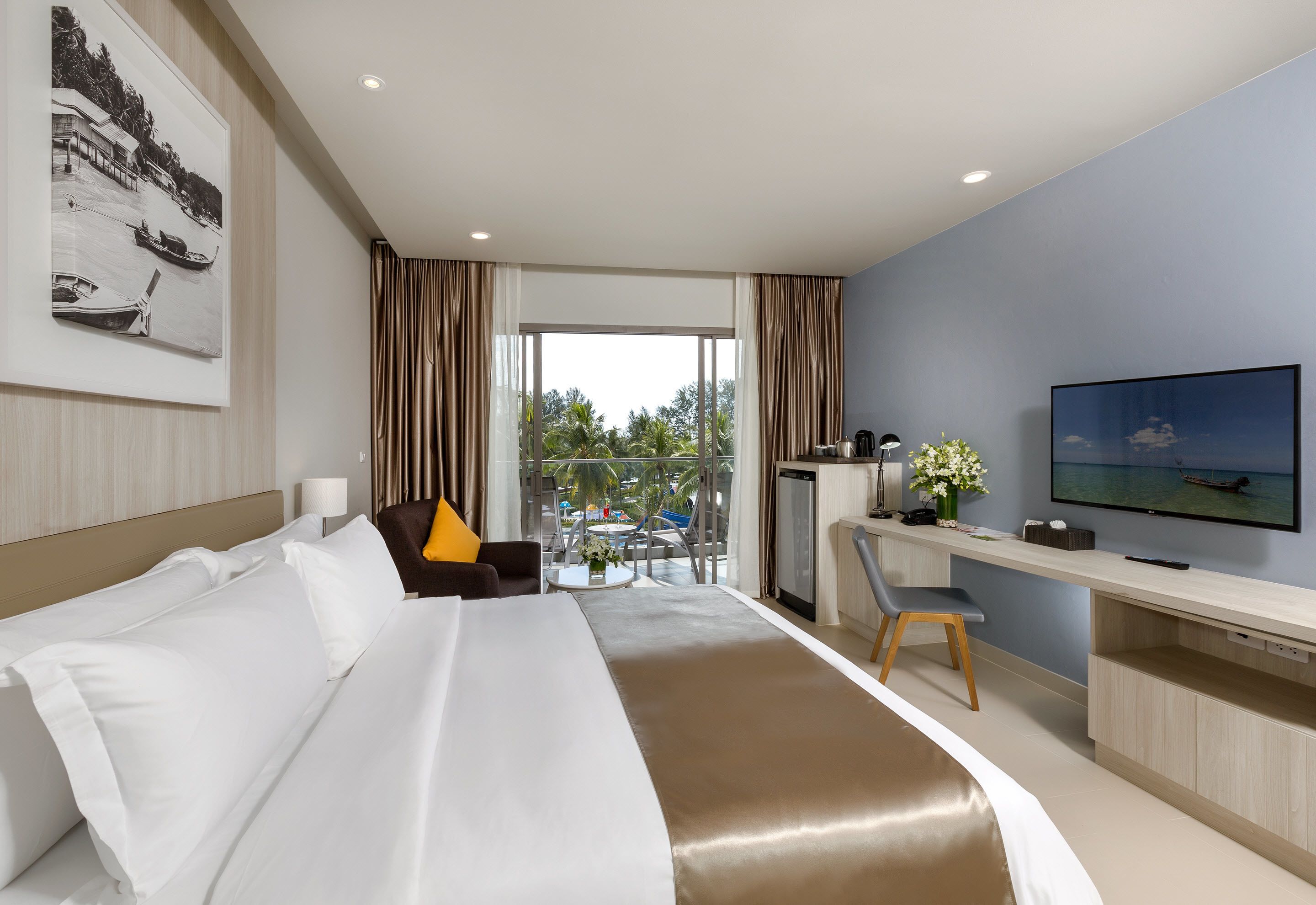 Habitación de hotel con cama, escritorio, televisión y vistas al exterior.