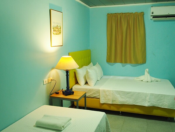 Una habitación de hotel con una cama, una mesita de noche con lámpara, aire acondicionado instalado en la pared y un cuadro enmarcado.