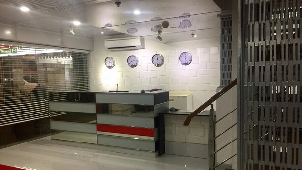 A reception area with a counter, multiple clocks on the wall, and an air conditioning unit. - New Era Mandaue Budget Hotel (Mandaue)