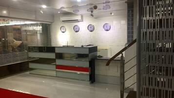 A reception area with a counter, multiple clocks on the wall, and an air conditioning unit.