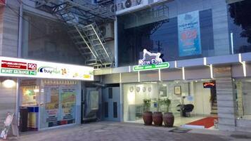 A hotel entrance with a 'New Era' sign, a money exchange, and a 24-hour service.