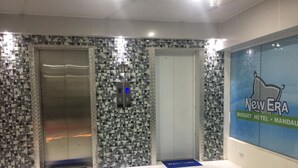 A lobby with mosaic tile walls, two elevators, and a 'New Era Budget Hotel' sign. - New Era Mandaue Budget Hotel (Mandaue)