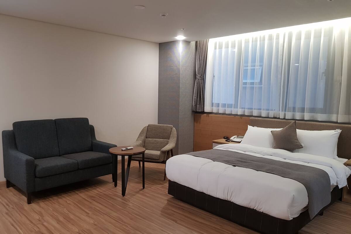 Ein Hotelzimmer mit einem Bett, einer dunklen Couch, einem kleinen Tisch und einem Stuhl.