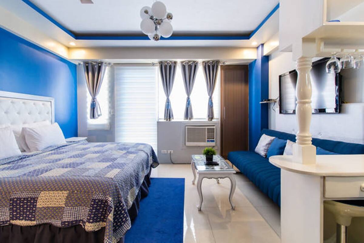 Une chambre moderne avec un grand lit, un canapé, une petite table et un téléviseur.