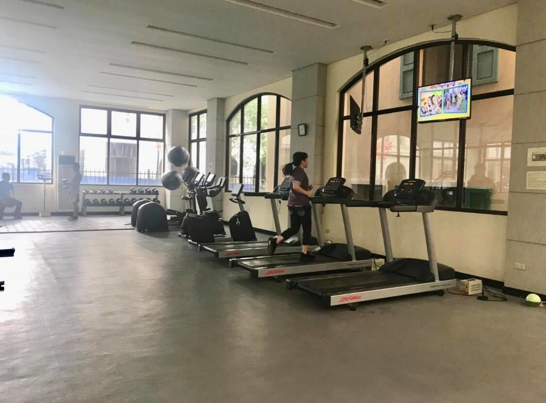 A gym with treadmills, weights, and a TV screen.