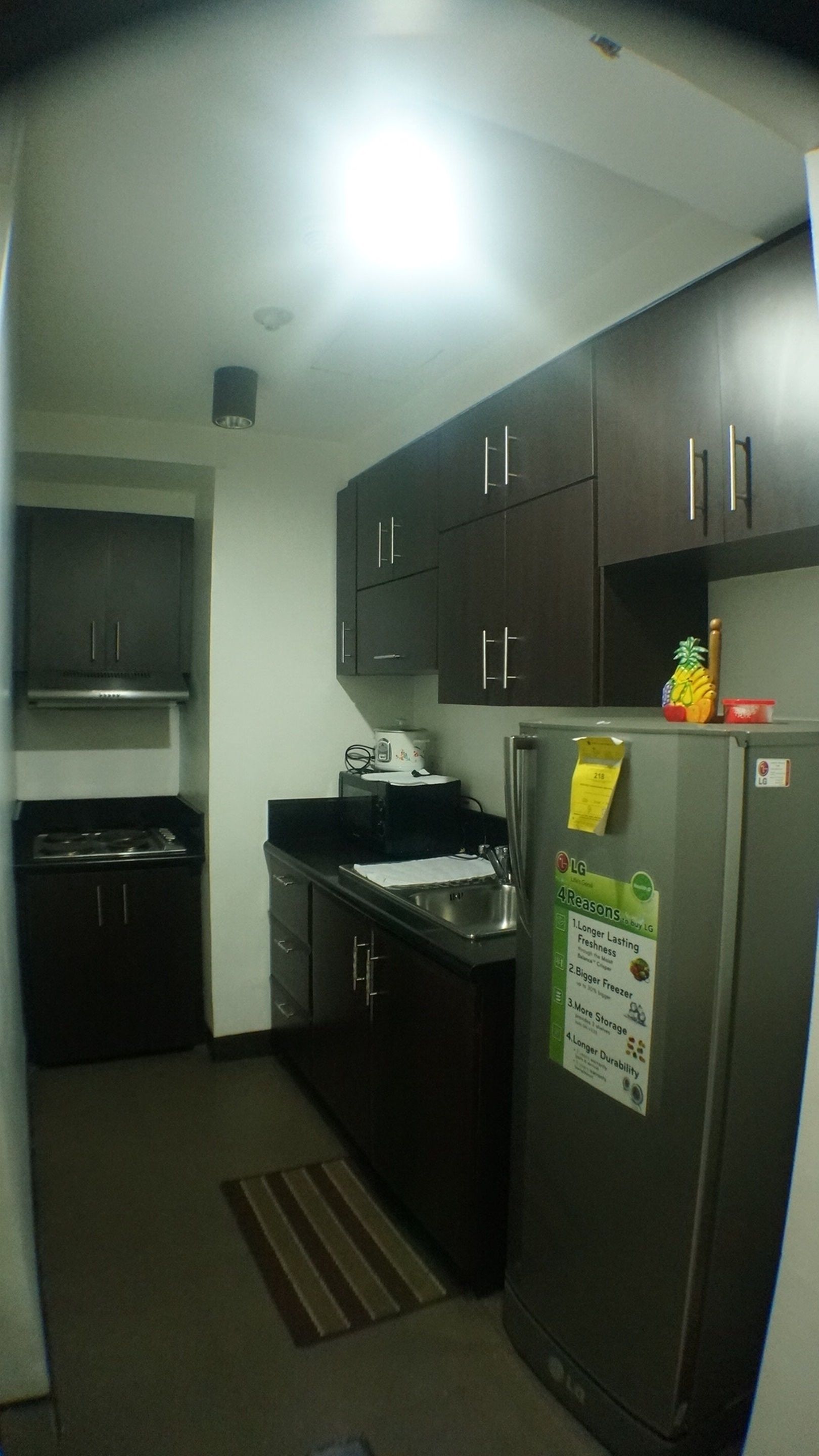 A compact kitchen with dark cabinets, a stainless steel refrigerator, and a microwave.