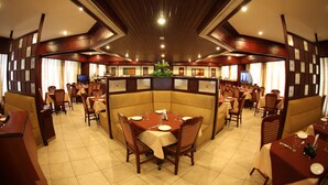 A restaurant with a central booth seating area, multiple dining tables, and a tiled floor. - Rathna Residency (Coimbatore)