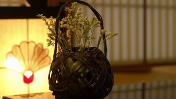 A woven basket with flowers on a reflective surface.