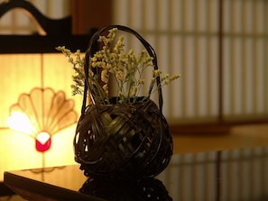 A woven basket with flowers on a reflective surface. - Asama Onsen Izumiso (Matsumoto)