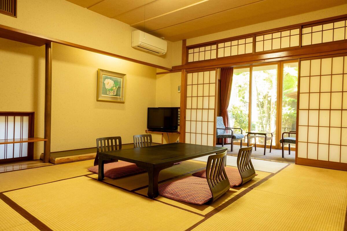 A traditional Japanese room with tatami flooring, a low table, and chairs.