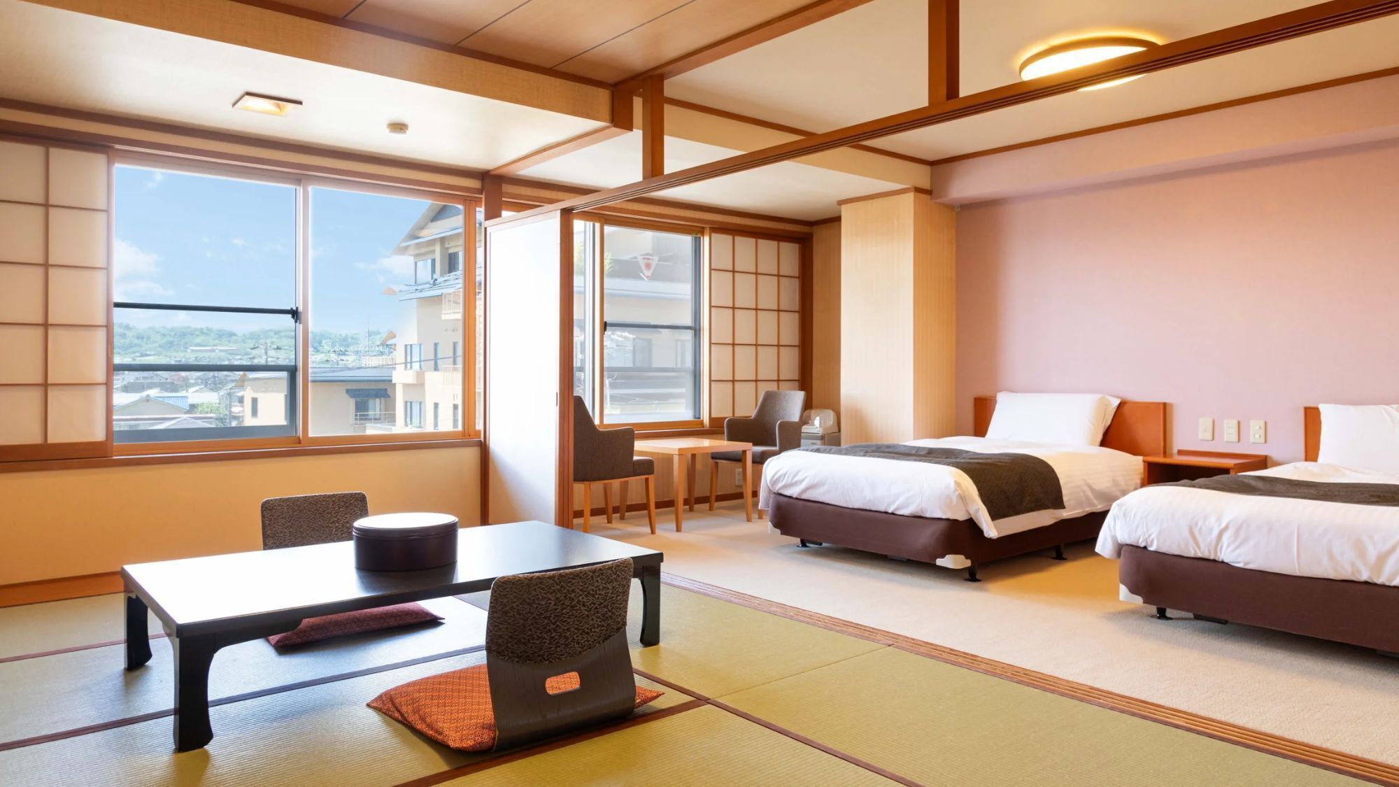 Une chambre d’hôtel avec deux lits, un bureau, une chaise et de grandes fenêtres.