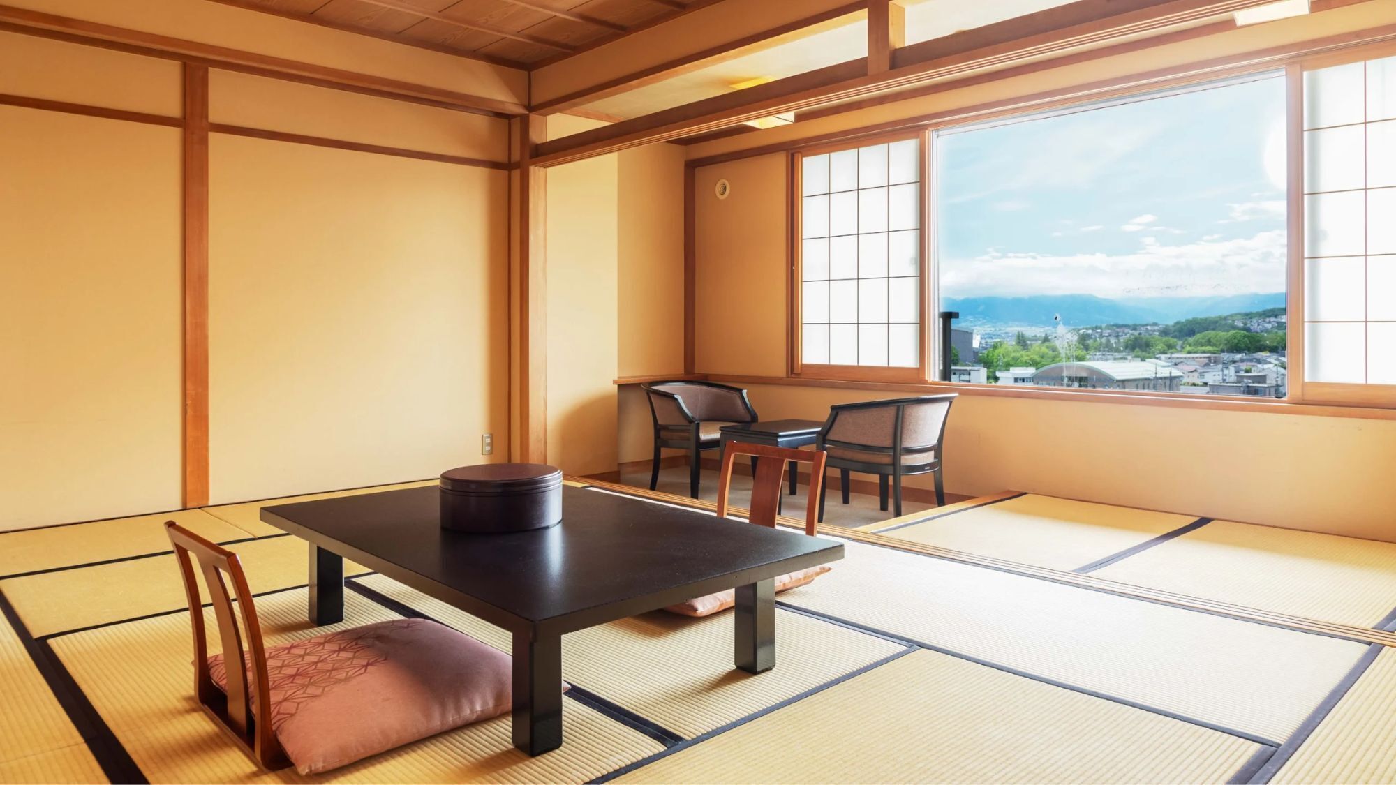 A traditional Japanese room with tatami flooring, a low table, and chairs.