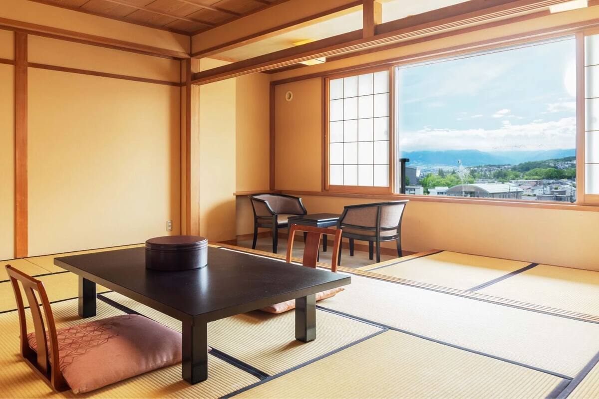 A traditional Japanese room with tatami flooring, a low table, and chairs.