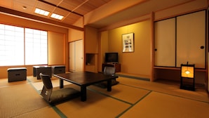 A traditional Japanese room with tatami flooring, a low table, cushions, a television, and sliding doors. - Asama Onsen Izumiso (Matsumoto)