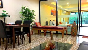 Un salon moderne avec une table basse en verre, un canapé et un coin repas comprenant des chaises et une table.
