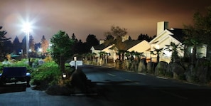 A residential street at night with houses on both sides, a bench, and a street lamp. - Skyline Pension (Jeju City)