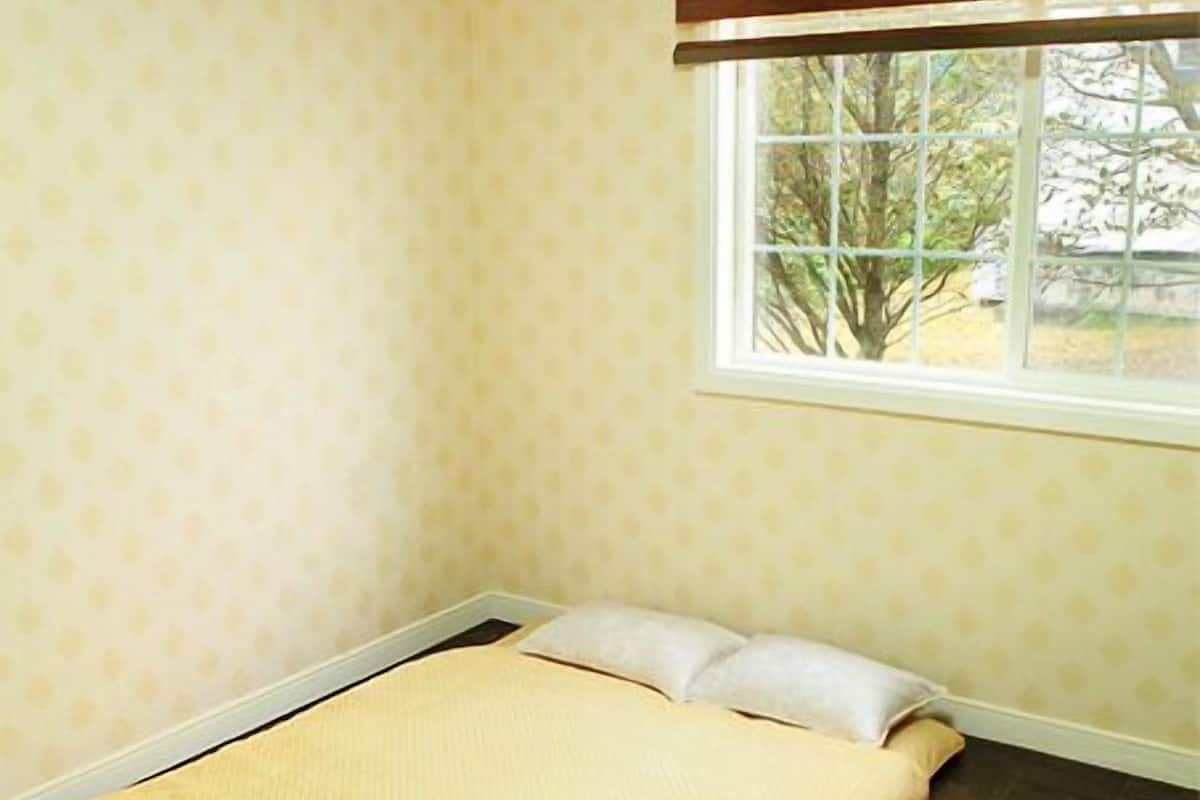 A room with a bed, a window with blinds, and a patterned wall.