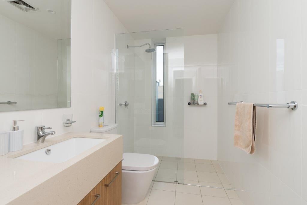 Un baño moderno con ducha de vidrio, lavamanos blanco y un inodoro.