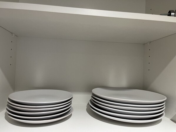 A stack of white plates on a white shelf in a room with white walls and a white ceiling.