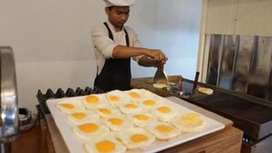 Un chef prepara huevos fritos en una plancha en una cocina.