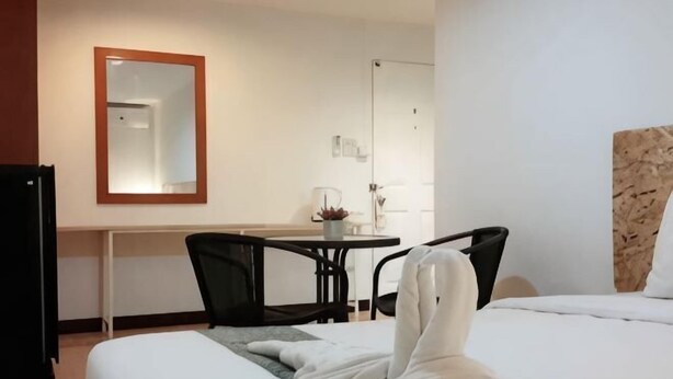 Una habitación de hotel con una cama, un escritorio, una silla y un espejo.