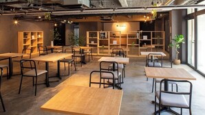 Ett modernt café med träbord och stolar, hyllor med växter och en skylt med texten ”zumya”.