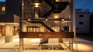 En modern byggnad med en framträdande trappa och en skylt med texten ”izumiya”.