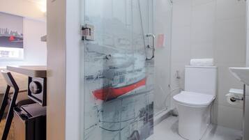 Un baño moderno con cabina de ducha de vidrio, inodoro blanco y lavamanos.
