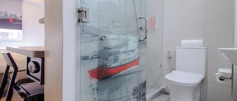 Un baño moderno con cabina de ducha de vidrio, inodoro blanco y lavamanos.