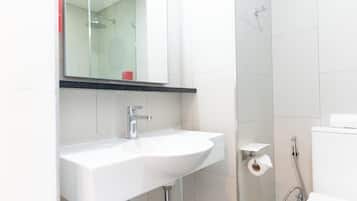 A modern bathroom with a white sink, a mirror above it, a shower area, and a toilet.