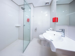 Un baño moderno con cabina de ducha de vidrio, un lavamanos blanco y un inodoro.