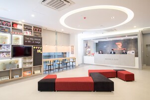 A modern reception area with a bar, seating, and a TV.