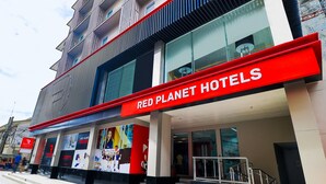 A Red Planet Hotels building with a modern facade, large windows, and a prominent red sign.