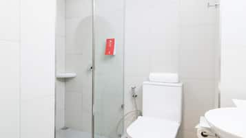 Un baño moderno con ducha de vidrio, inodoro blanco y lavamanos.