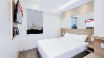 Una habitación de hotel con una cama, un televisor, un cartel de paisaje urbano y un espejo.