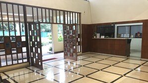 A reception area with a tiled floor, a reception desk, and a wooden partition with glass panels. - Park Hotel and Resort (Anekal)