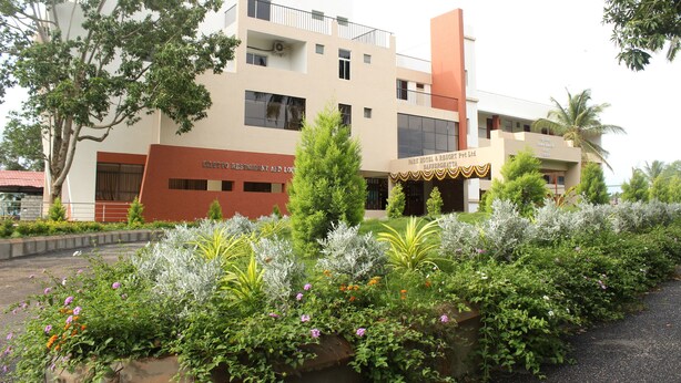 A hotel with a modern design, featuring a restaurant and lounge area, surrounded by well-maintained gardens and trees. - Park Hotel and Resort (Anekal)