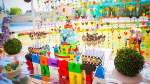 A colorful children's party setup with a Mickey Mouse themed cake, lollipops, and a backdrop of hanging Mickey Mouse decorations. - Park Hotel and Resort (Anekal)