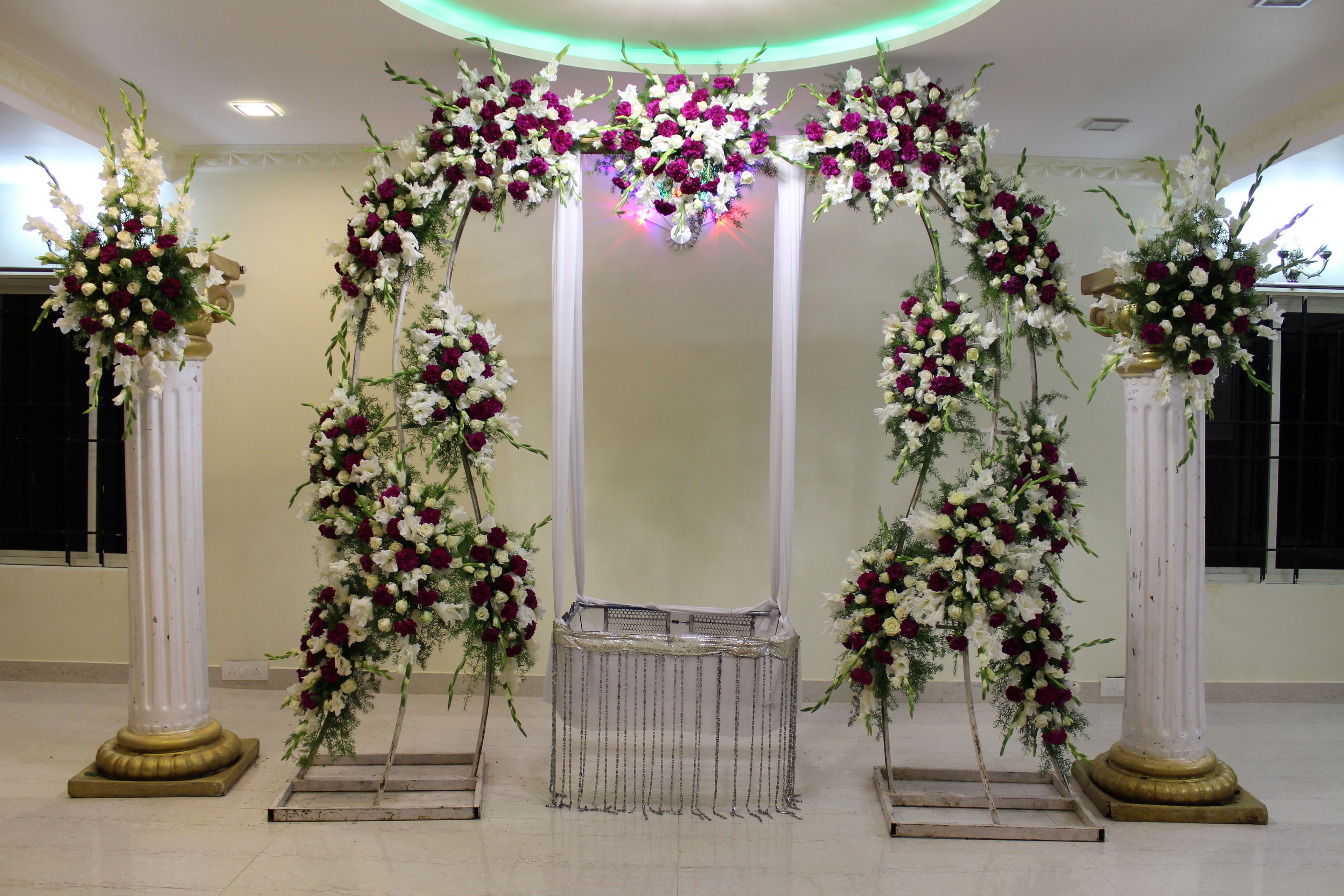 A reception area with a floral archway, a reception desk, and a white column.