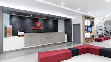 A modern reception area with a Red Planet logo, a counter, and a seating area with red and black cushions.