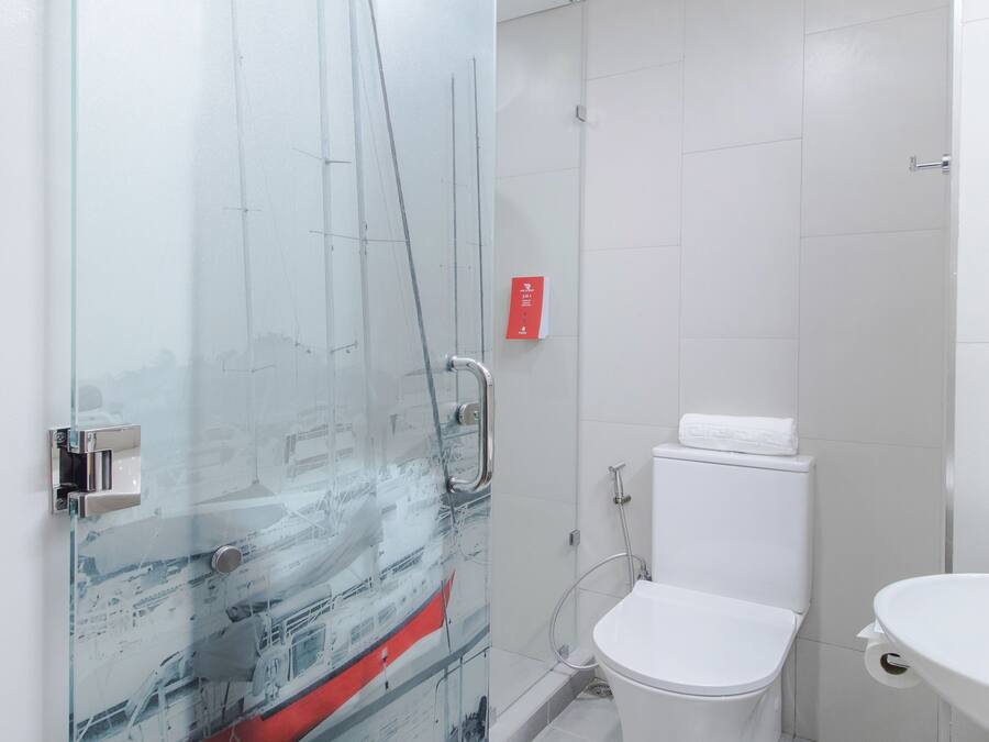 A modern bathroom with a glass shower enclosure, a white toilet, and a sink.