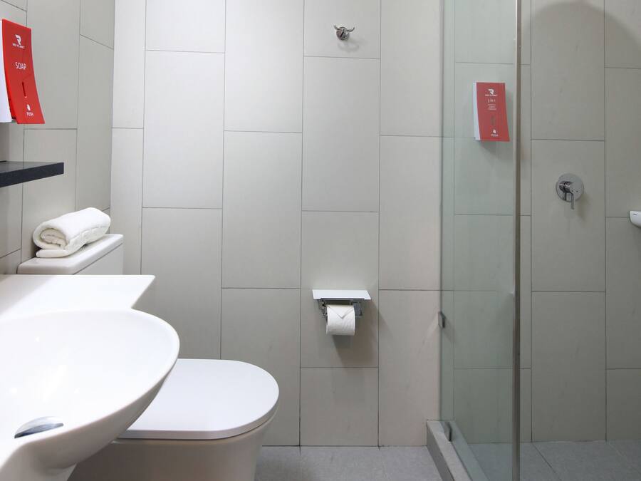 A modern bathroom with a glass-enclosed shower, a white sink, and a toilet.